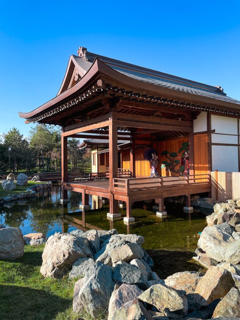 Beautiful traditional Japanese pavilion with a tranquil pond and garden setting under a clear blue sky.